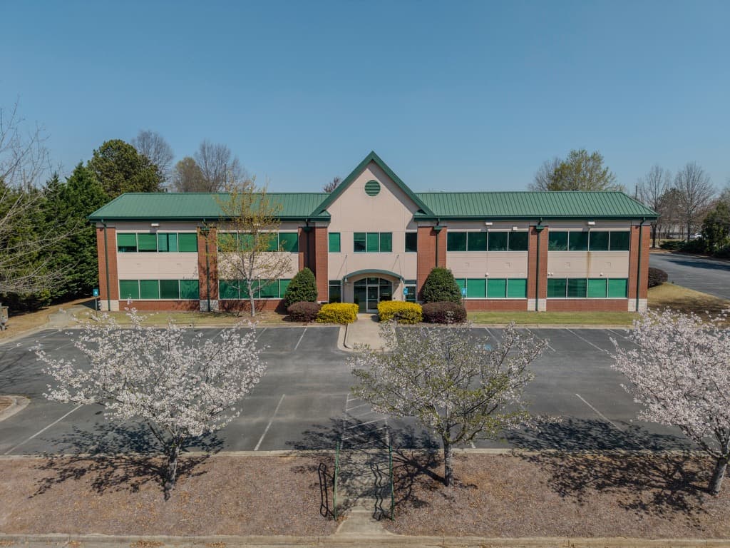 Front-facing aerial view of an executive office center with blooming trees