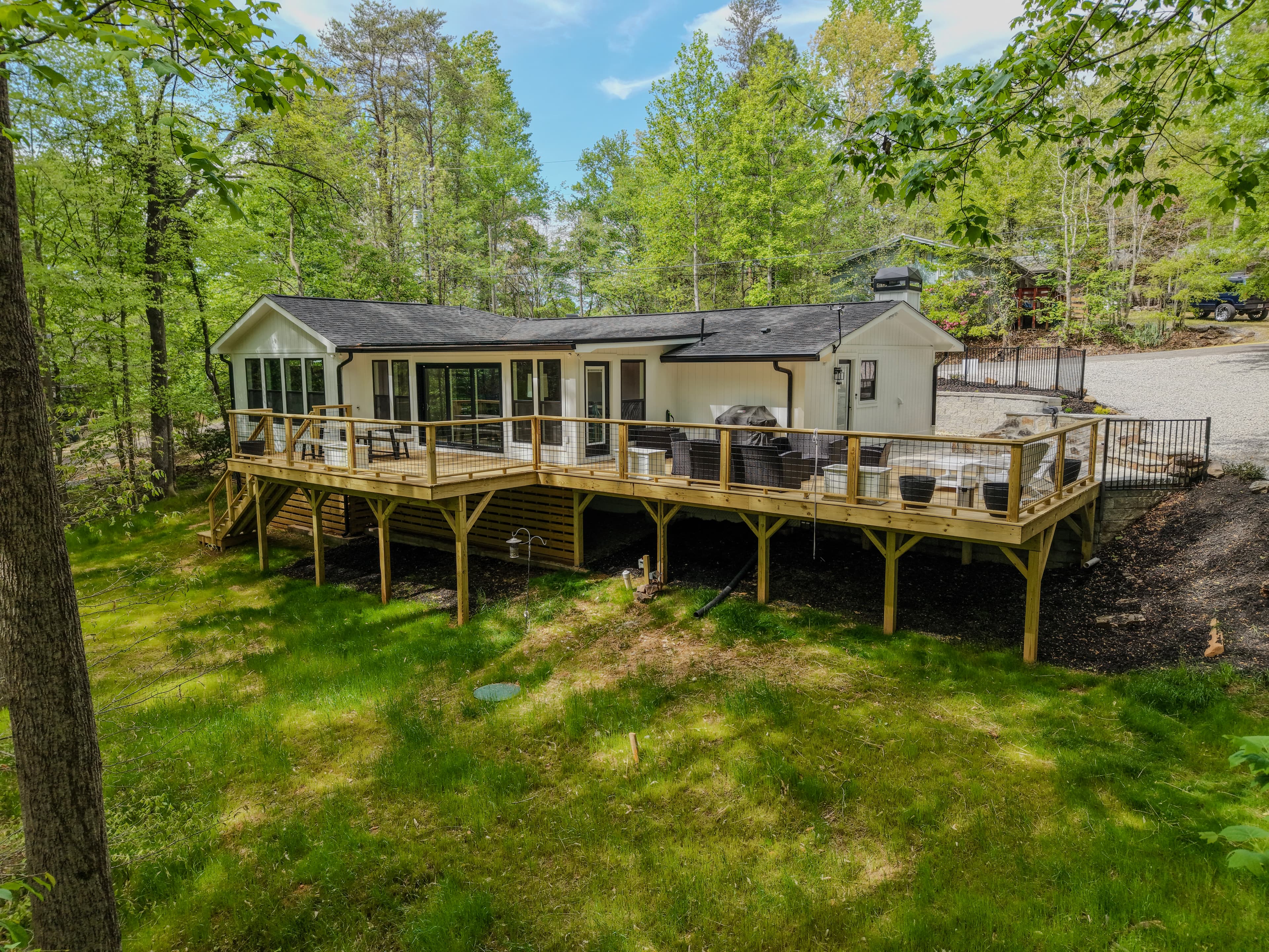 Rear exterior view of a house with a large deck and wooded surroundings